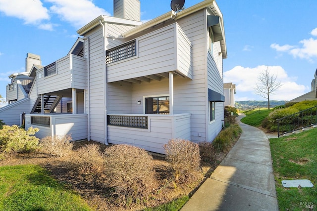 view of side of property featuring a chimney and a balcony