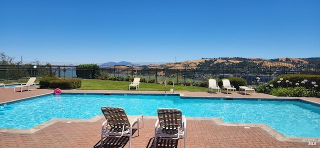 community pool with a lawn, fence, a patio, and a mountain view