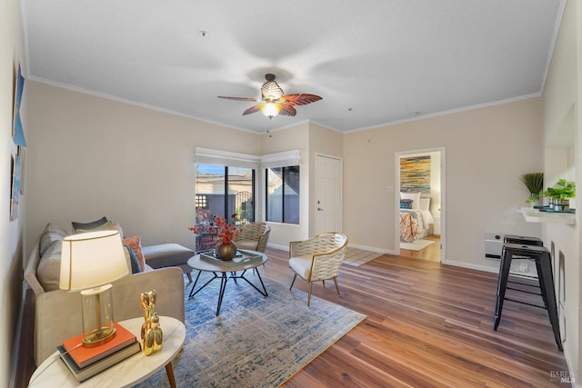 living room with crown molding, baseboards, and wood finished floors