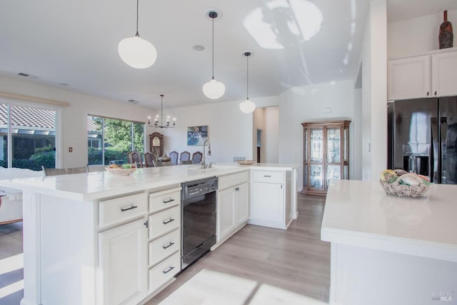 kitchen featuring a kitchen island with sink, hanging light fixtures, black appliances, and white cabinets