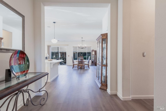 corridor with hardwood / wood-style floors and an inviting chandelier