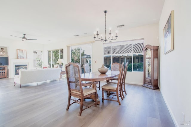 dining room with ceiling fan with notable chandelier and light hardwood / wood-style flooring