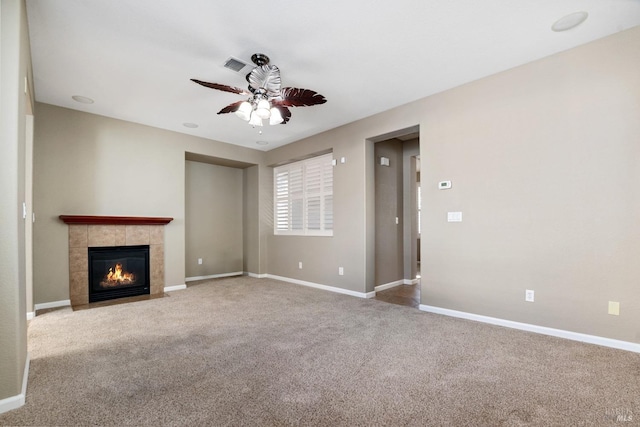 unfurnished living room with ceiling fan, a tile fireplace, and carpet