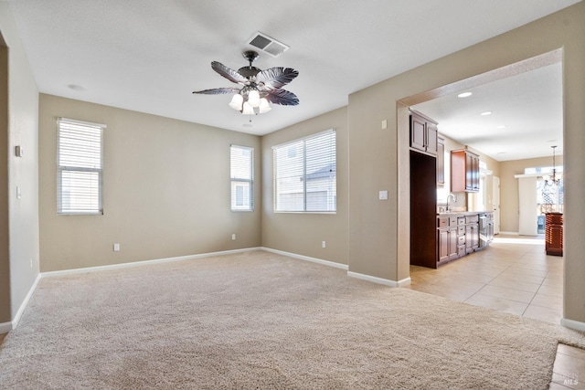 spare room featuring ceiling fan with notable chandelier, sink, and light colored carpet