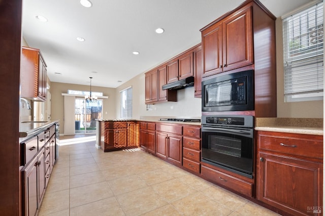 kitchen featuring black microwave, wall oven, a chandelier, pendant lighting, and sink