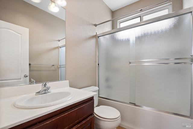 full bathroom with bath / shower combo with glass door, vanity, and toilet