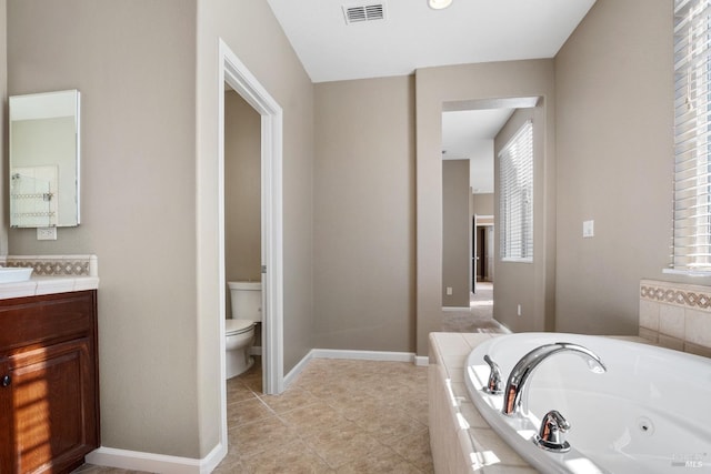 bathroom featuring tile patterned floors, toilet, vanity, and tiled tub
