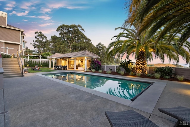 view of swimming pool featuring a patio area, a fenced backyard, a storage structure, and an outbuilding