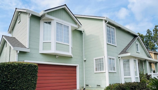 view of property exterior with a garage and roof with shingles