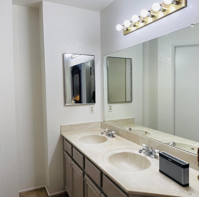 bathroom with double vanity, a sink, and a textured wall
