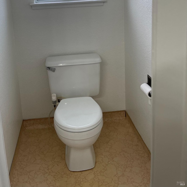 bathroom with baseboards and toilet