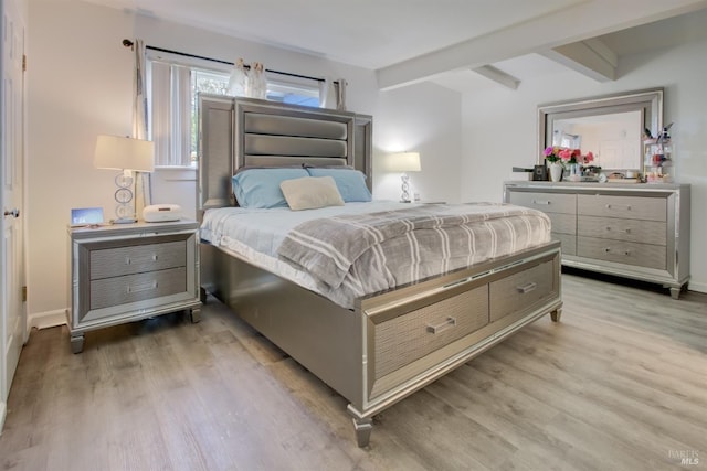 bedroom featuring beam ceiling, baseboards, and light wood-style floors