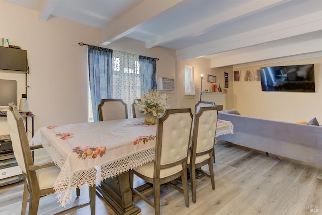 dining room with beamed ceiling, a wall unit AC, and light hardwood / wood-style flooring