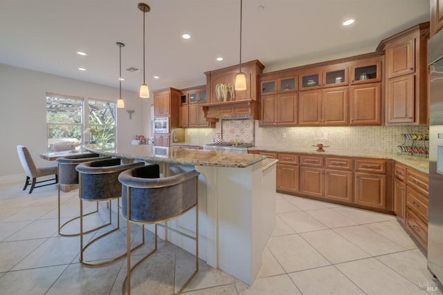 5319 Bayridge Ct, Fairfield, CA 94534 - kitchen featuring brown cabinets, light stone counters, backsplash, a kitchen island, and light tile patterned floors