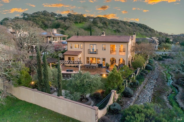 5319 Bayridge Ct, Fairfield, CA 94534 - back of house at dusk with a chimney, a tile roof, stucco siding, fence, and a patio
