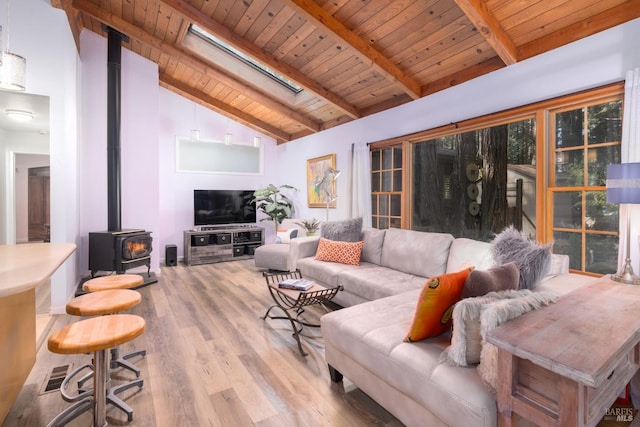 living room with a wood stove, lofted ceiling with skylight, light hardwood / wood-style floors, and wood ceiling