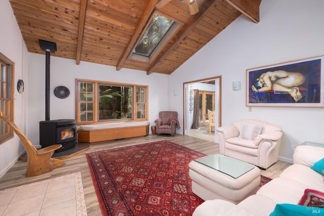 tiled living room with a wood stove, wood ceiling, a skylight, high vaulted ceiling, and beamed ceiling