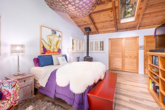 bedroom with light hardwood / wood-style flooring, vaulted ceiling with beams, a wood stove, and wooden ceiling