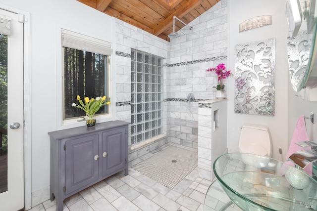 bathroom featuring vaulted ceiling with beams, a tile shower, and wooden ceiling