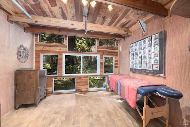 bedroom with wood ceiling, light hardwood / wood-style floors, multiple windows, beamed ceiling, and wooden walls