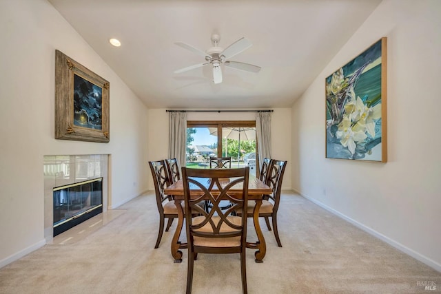 dining room with light carpet, lofted ceiling, and a premium fireplace