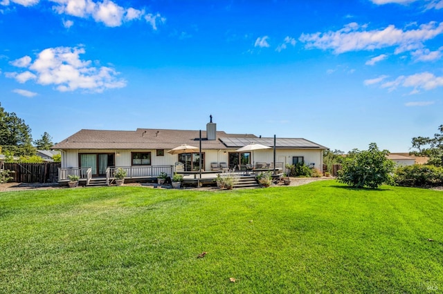 back of property with a wooden deck and a lawn