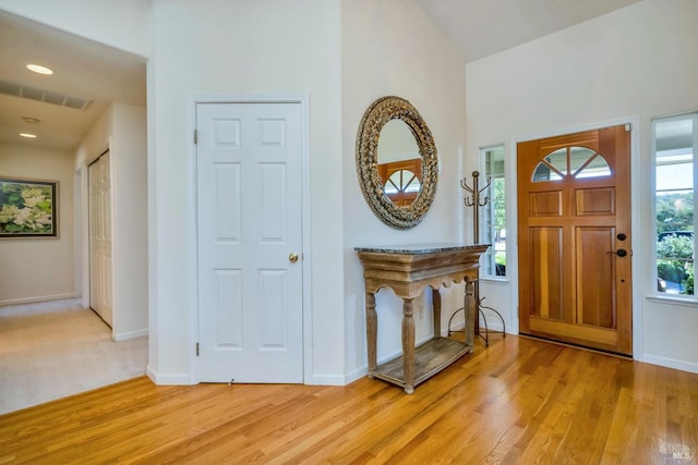 foyer entrance with light hardwood / wood-style flooring and lofted ceiling