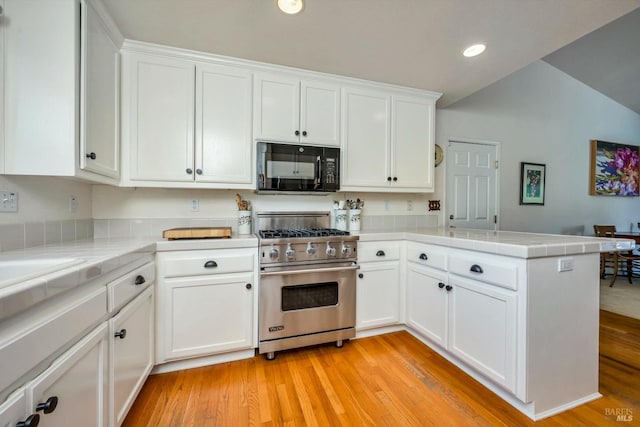 kitchen featuring white cabinetry, kitchen peninsula, and luxury stove