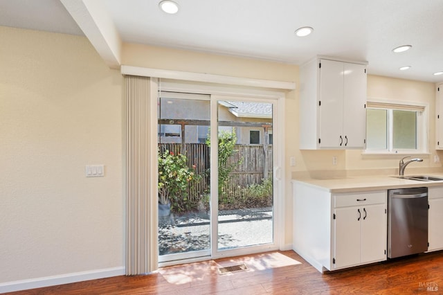 kitchen with light countertops, stainless steel dishwasher, a sink, and white cabinetry