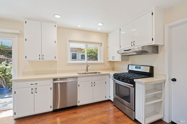 kitchen with stainless steel appliances, light countertops, white cabinets, a sink, and under cabinet range hood