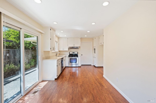 kitchen featuring dark wood finished floors, appliances with stainless steel finishes, light countertops, white cabinetry, and a sink