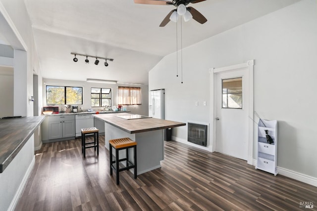 kitchen with white appliances, gray cabinetry, a breakfast bar area, and dark hardwood / wood-style floors