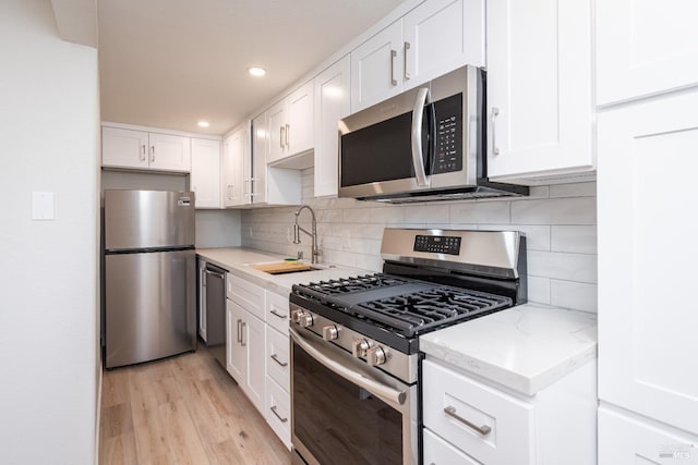 1008 Evans Ave, Napa, CA 94559 - kitchen with white cabinets, light wood-style flooring, a sink, and stainless steel appliances