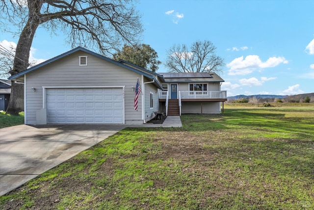 ranch-style home featuring a garage, solar panels, a mountain view, and a front yard