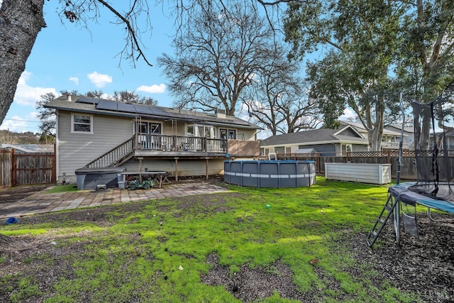 19839 Mountain Mdw S, Hidden Valley Lake, CA 95467 - rear view of house featuring a swimming pool side deck, a lawn, a patio area, solar panels, and a trampoline