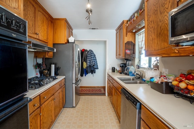 kitchen featuring visible vents, appliances with stainless steel finishes, under cabinet range hood, light floors, and a sink