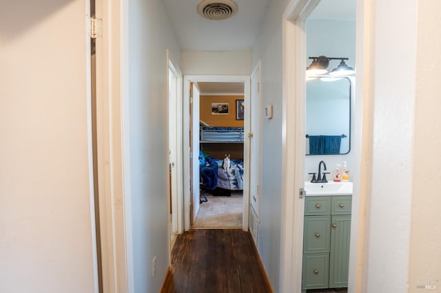 corridor featuring dark wood-type flooring, a sink, and visible vents