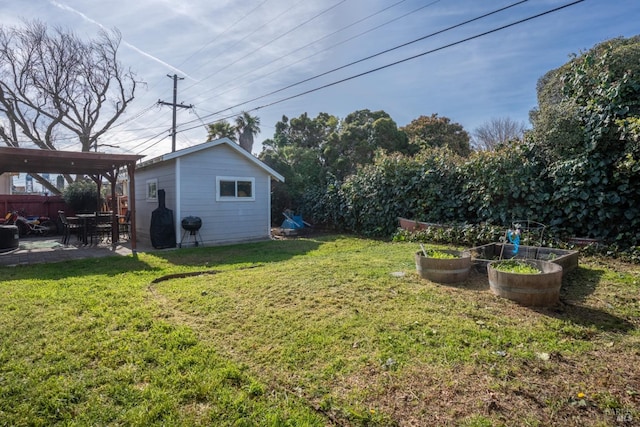 view of yard featuring fence, a vegetable garden, an outbuilding, and a patio