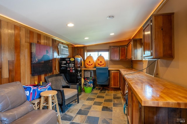 interior space with brown cabinetry, an AC wall unit, built in study area, open floor plan, and butcher block countertops