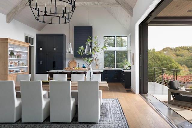 dining area featuring high vaulted ceiling, wooden ceiling, beam ceiling, light wood finished floors, and an inviting chandelier