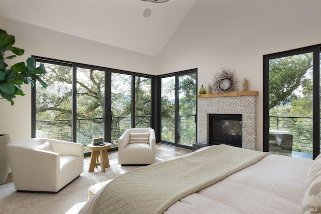 bedroom with carpet floors, a fireplace, high vaulted ceiling, and multiple windows