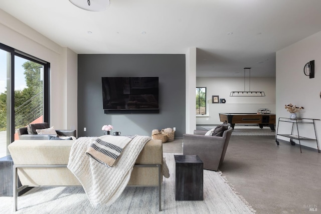 living area with finished concrete flooring, billiards, and a healthy amount of sunlight