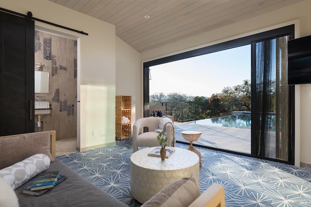 sitting room featuring vaulted ceiling, a barn door, wooden ceiling, and baseboards