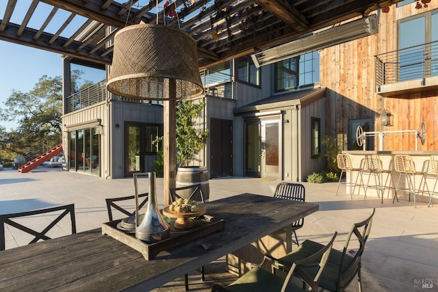 view of patio / terrace featuring outdoor dry bar, french doors, outdoor dining area, and a pergola