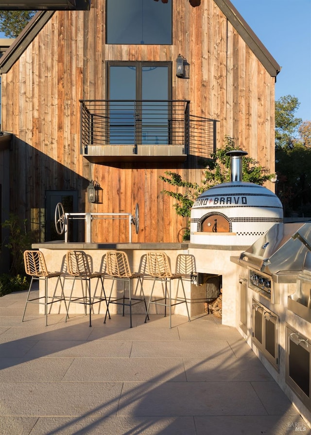 view of patio / terrace with exterior kitchen, a grill, outdoor dry bar, and a balcony