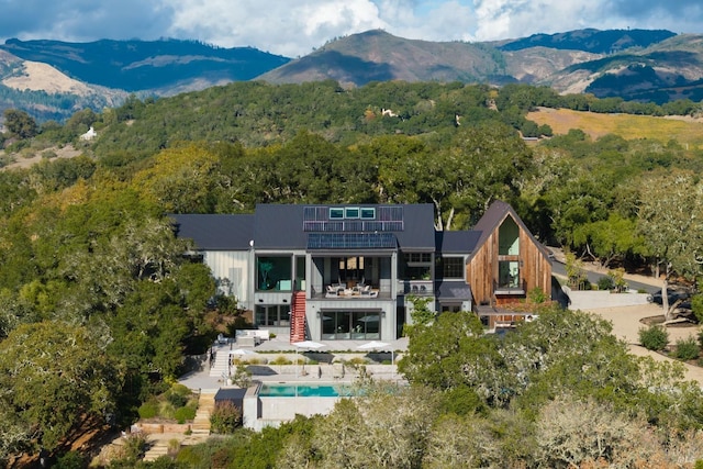 exterior space featuring solar panels, stairway, a patio area, a mountain view, and a wooded view