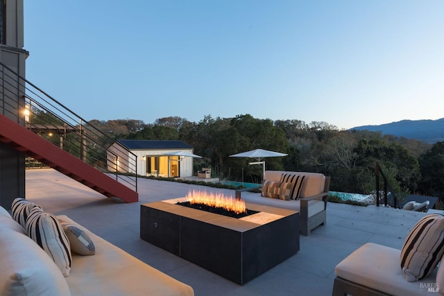 exterior space with a patio area, an outdoor living space with a fire pit, a mountain view, and an outbuilding