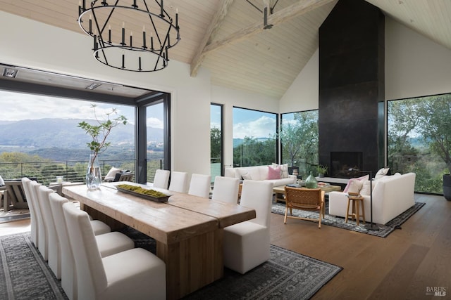 sunroom featuring lofted ceiling with beams, wooden ceiling, a mountain view, and a chandelier