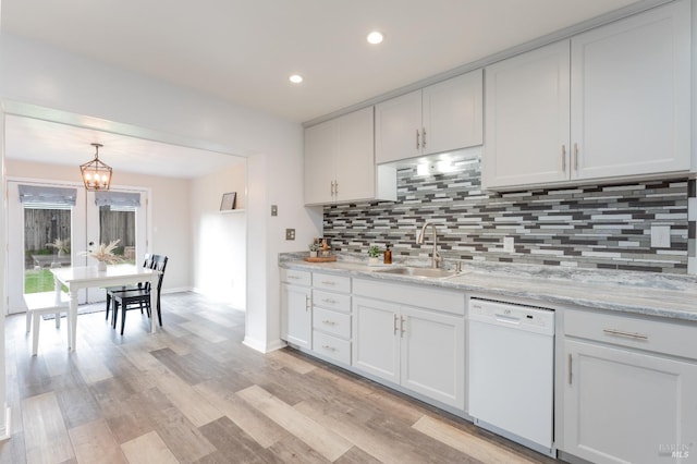 kitchen with a sink, hanging light fixtures, light wood-type flooring, decorative backsplash, and dishwasher