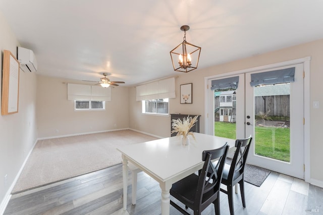 dining space with french doors, a wall unit AC, light wood finished floors, and baseboards